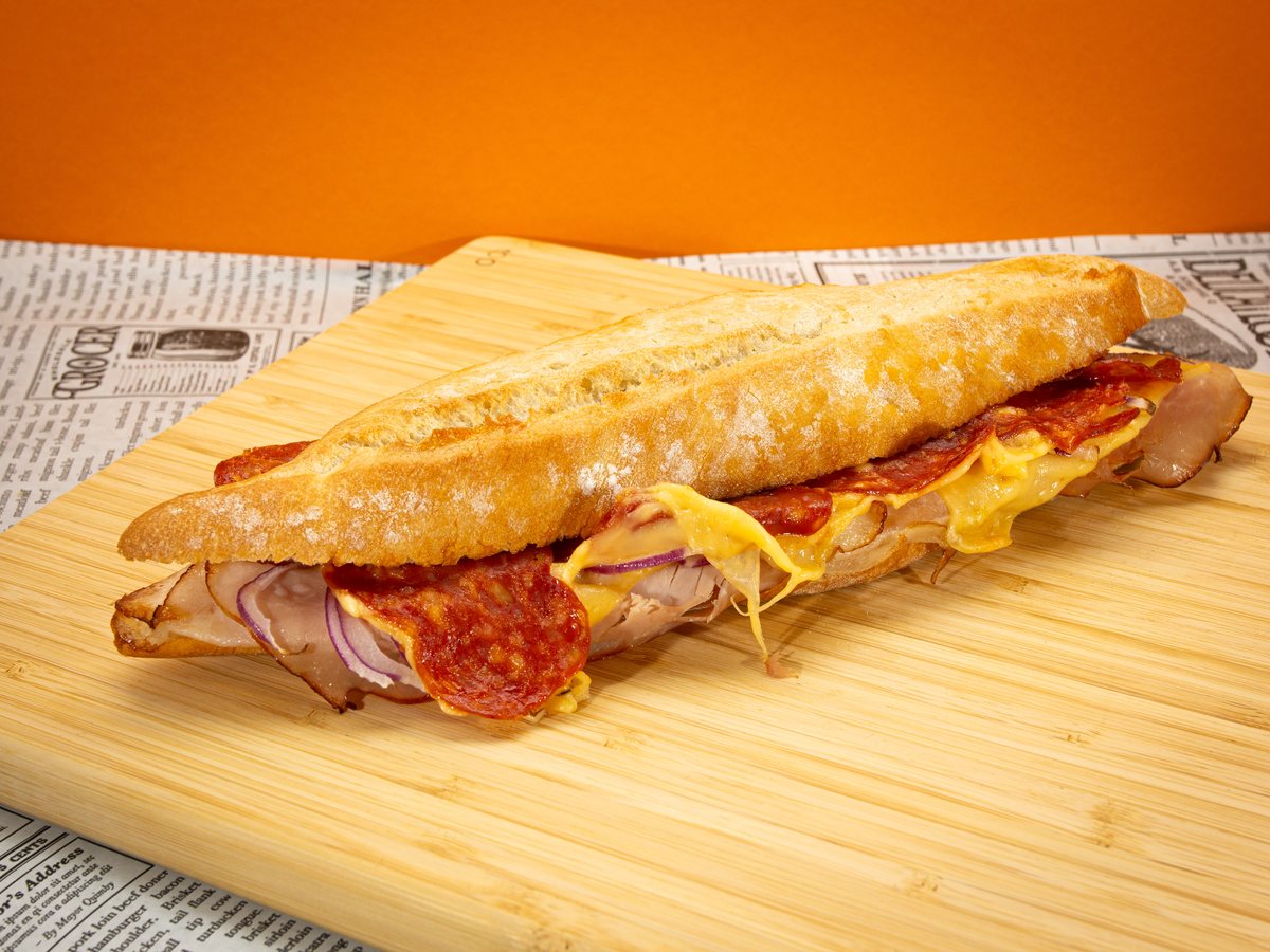 Broodje Nice met ham, salami, kaas en rode ui op een knapperig stokbrood
