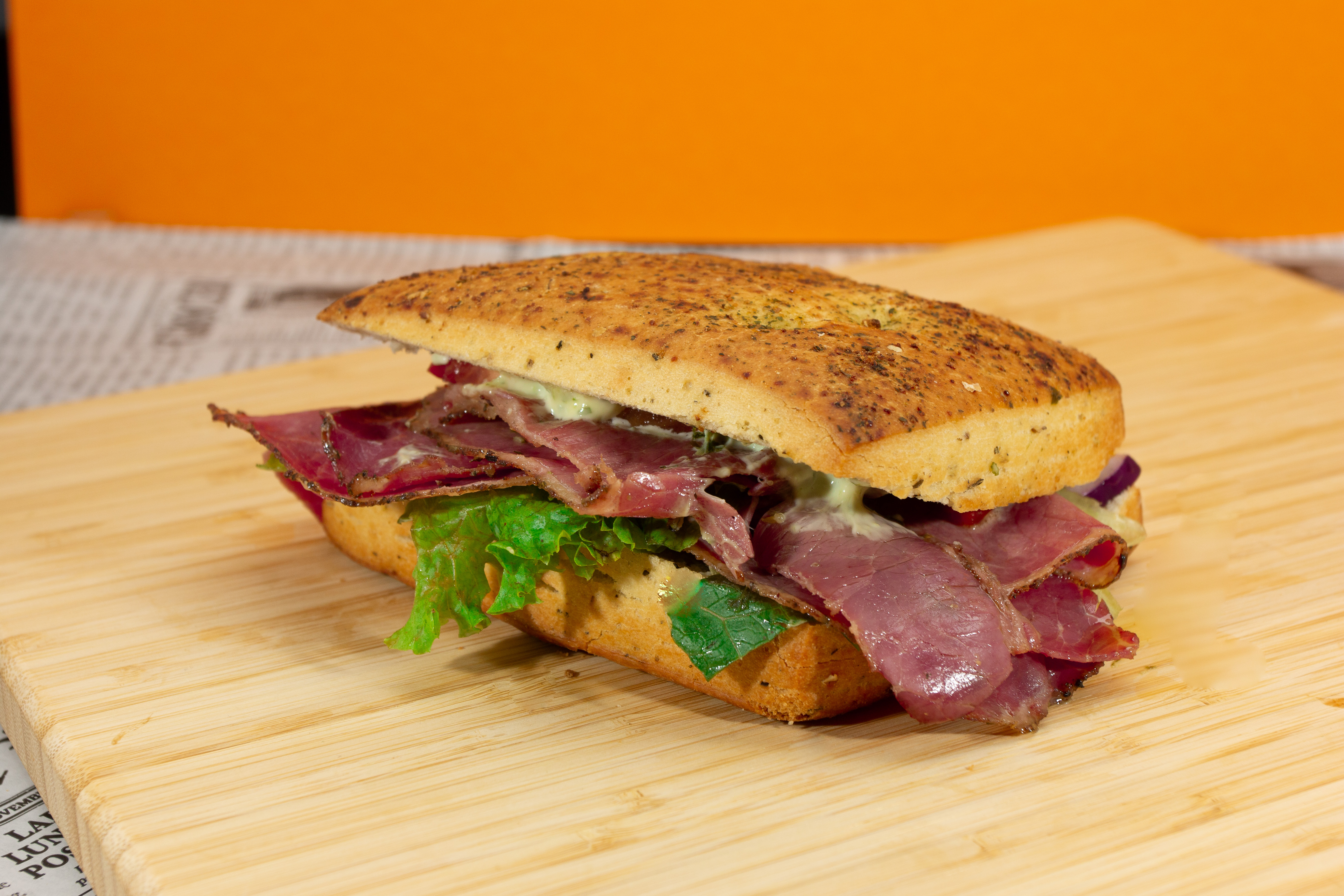 Focaccia met pastrami, kruidenolie, tomaat, rode ui en sla